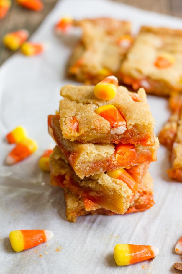 Candy corn on parchment paper with stack of Candy Corn Blondies.