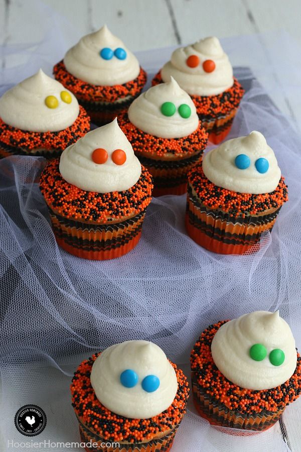 Orange and black cupcakes with white frosting and candy eyes to look like ghosts.