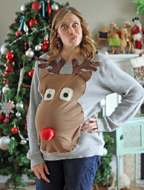 Pregnant woman wearing a Rudolph the red nosed reindeer sweater. 