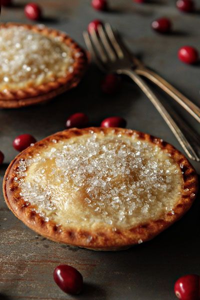 Two individual pear and Cranberry Pies with cranberries on table and two forks.