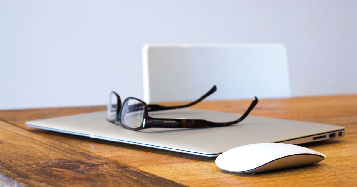 Laptop, glasses and computer mouse on table.