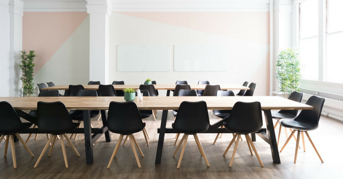 Wood tables and chairs lined up in office space.