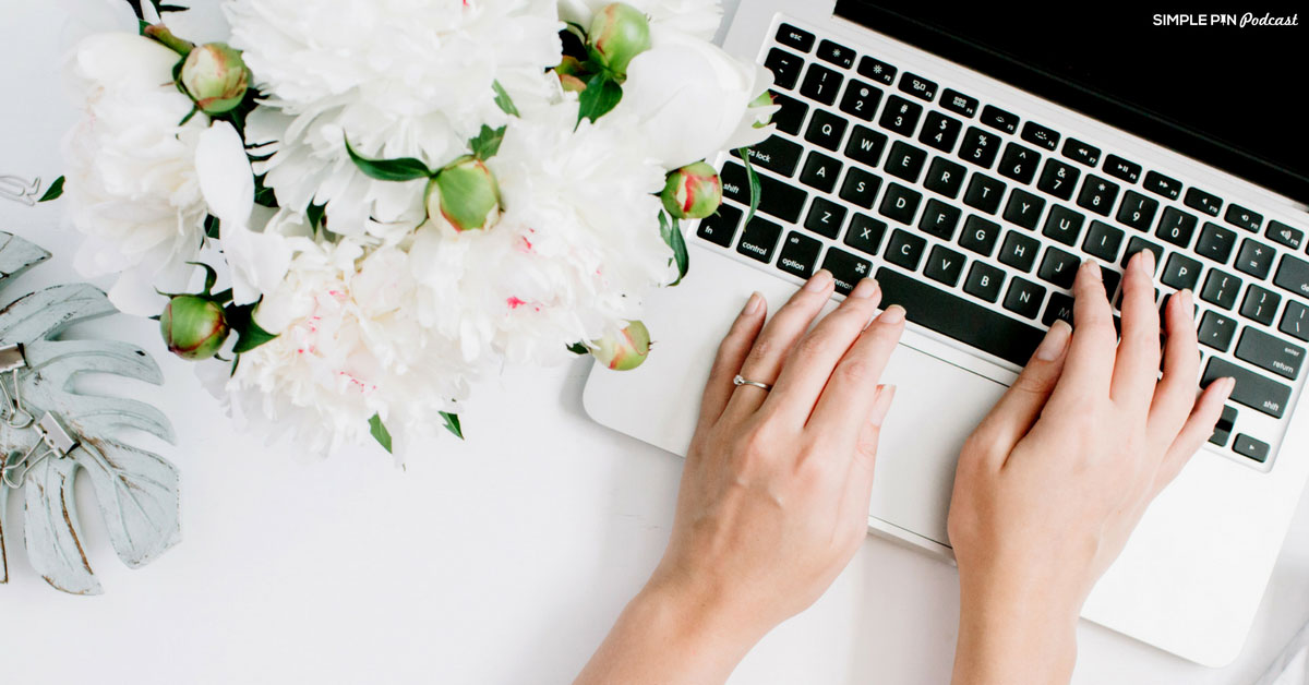 woman typing laptop next to white flowers.