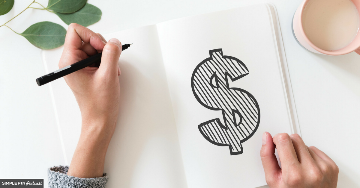 Woman's hand writing in notebook with a large $ sign.