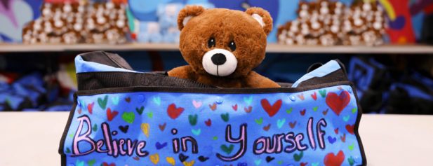 teddy bear holding a sign that says "Believe in yourself".