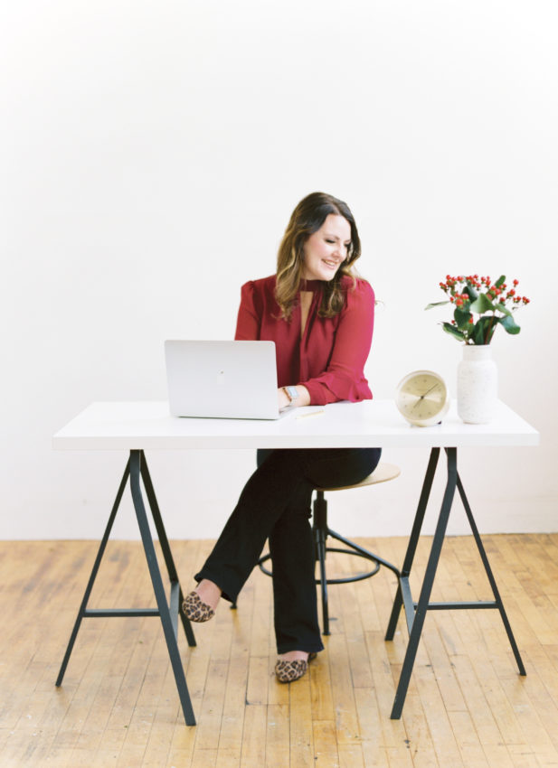 Simple Pin Media Services Professional woman (Kate Ahl) typing on computer at her desk.