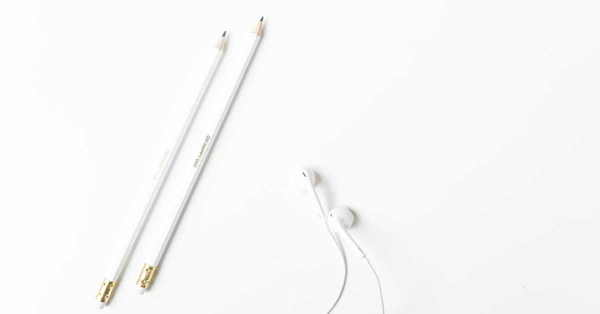 white tabletop with earbuds and pencils.