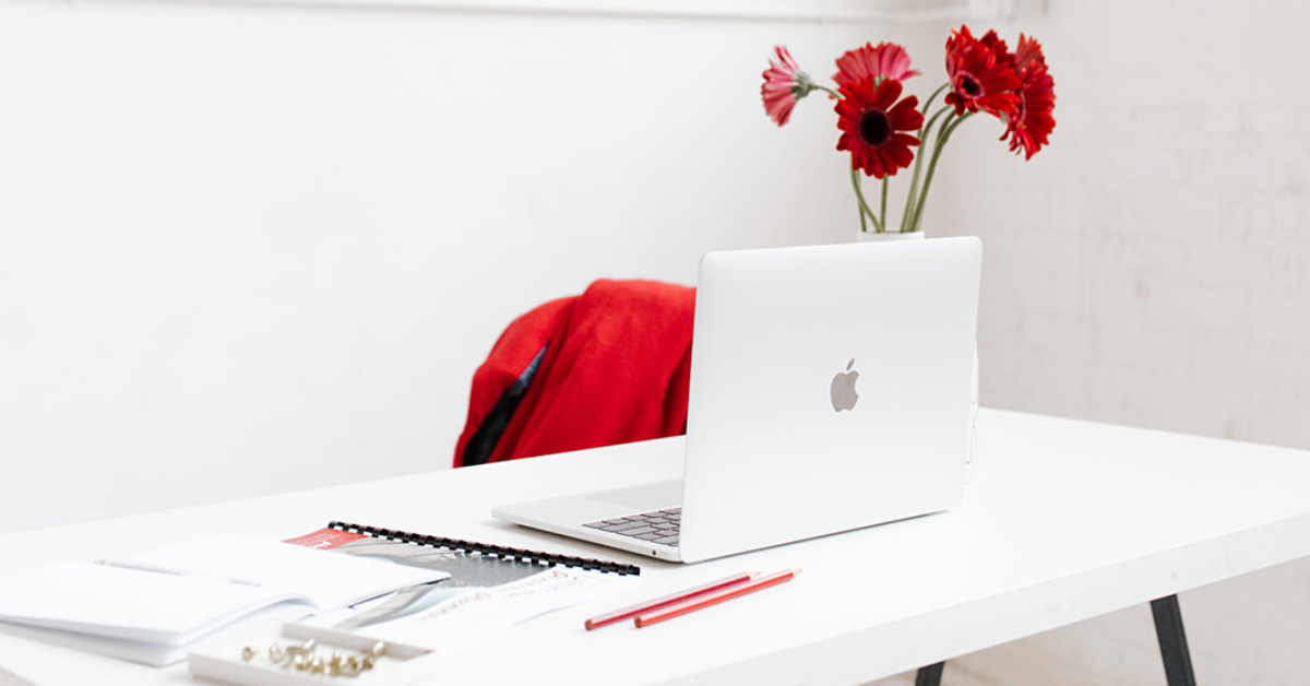 white desk with laptop and flowers.