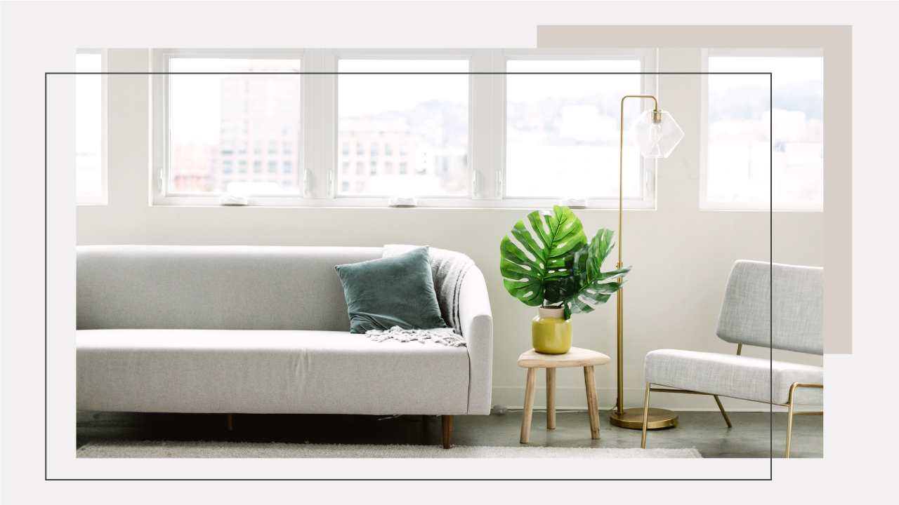 well lit room with white couch and green plant on stool