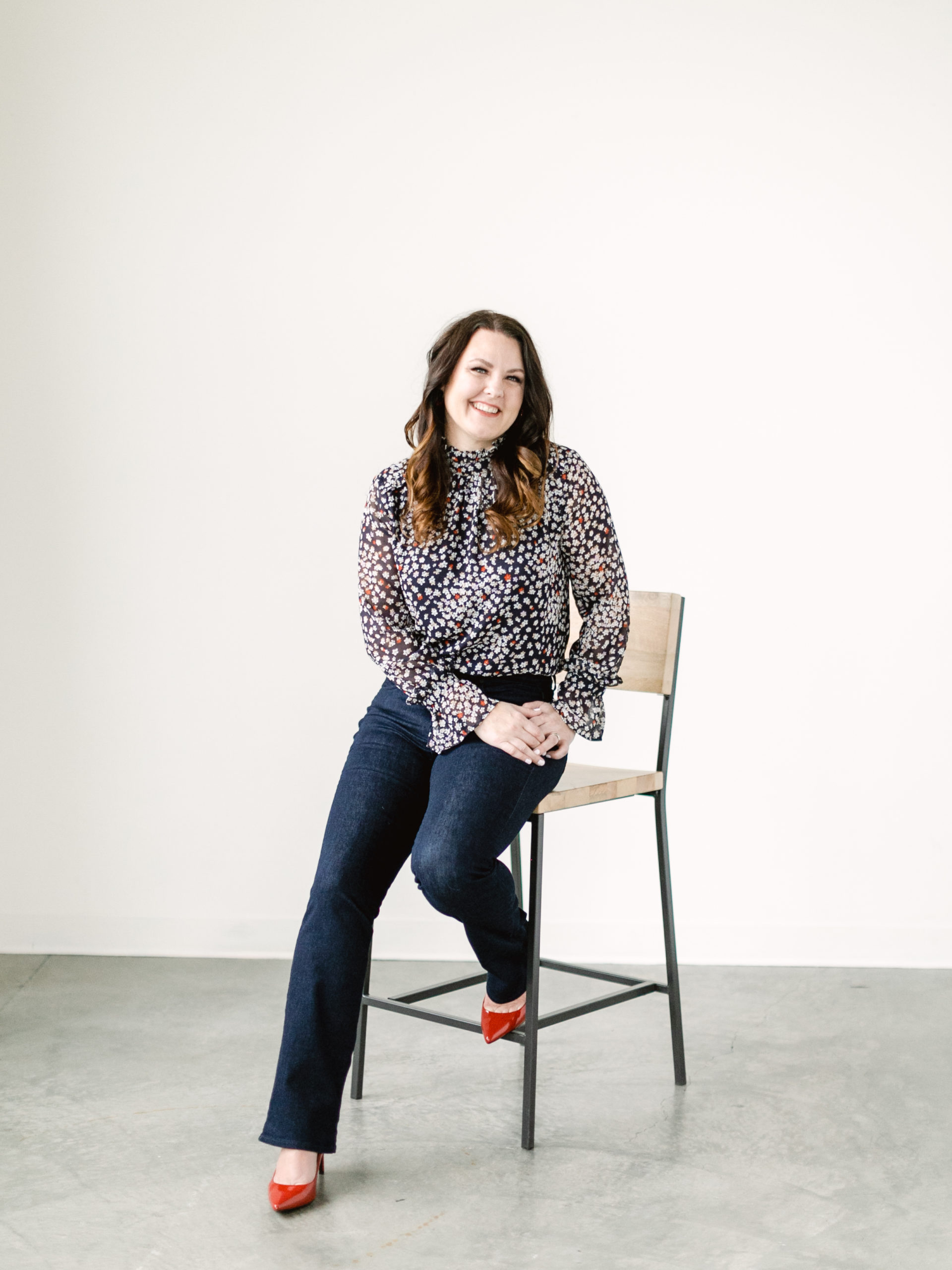 brandsession_marialambphotography021 (1) Woman with brown hair in flowered top and denim sitting on stool