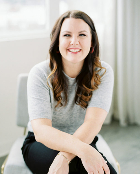 Kate Ahl sitting on a chair smiling.