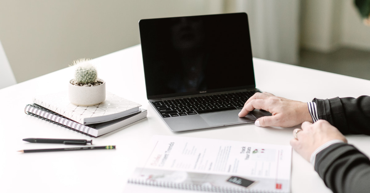 woman sitting at desk typing on laptop computer.