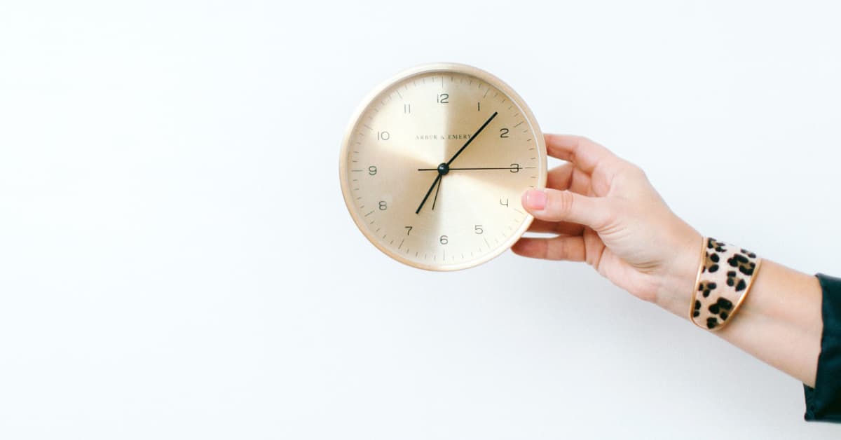 woman's hand holdng a gold clock.