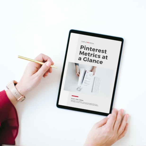 hand holding pen next to ipad with text - "pinterest metrics at a glance".