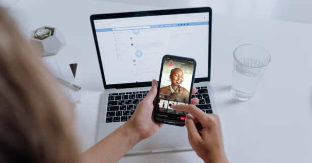 person sitting at desk holding mobile phone displaying a Pinterest TV episode.