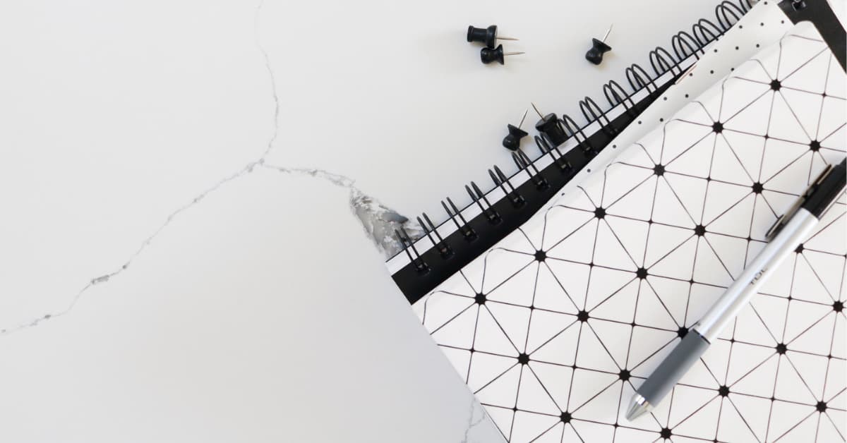 flat lay of black and white journal with black push pins lying on table.
