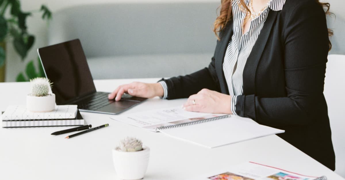 person in black jacket with hands on laptop.