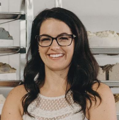 woman with dark hair and glasses smiling.