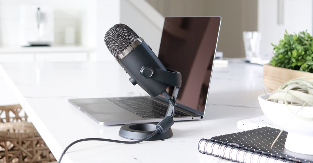 microphone and laptop sitting on white desk.