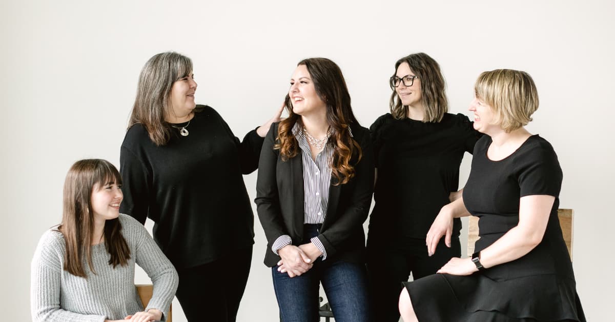 five women smiling at each other.