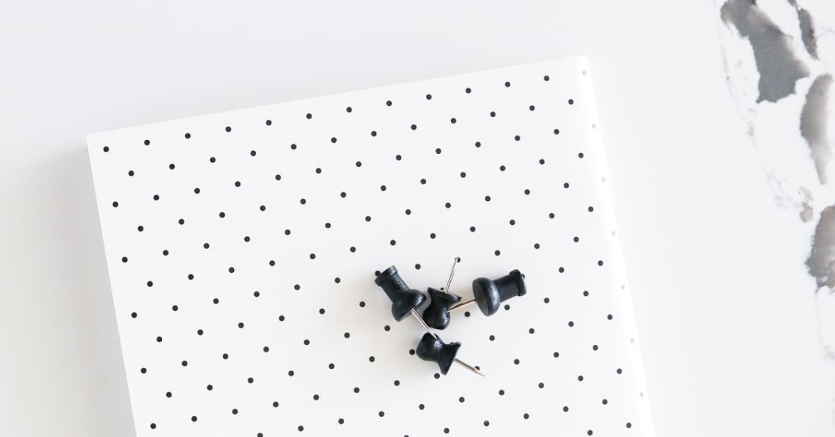 flat lay of journal with black polka dots with push pins on top.