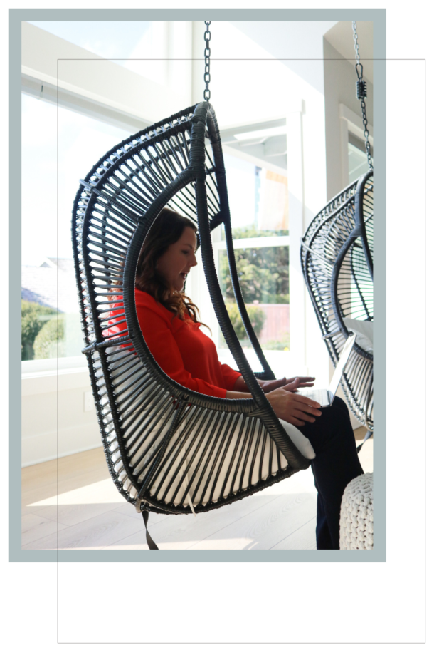 woman sitting in hanging chair on laptop.