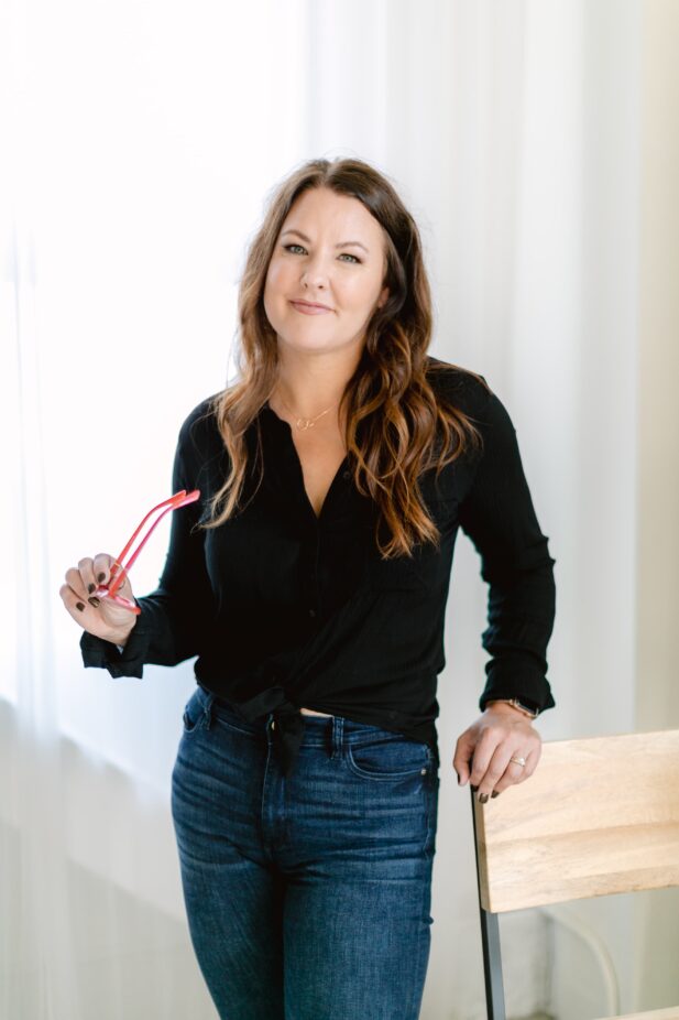 woman in black shirt and jeans holding glasses.