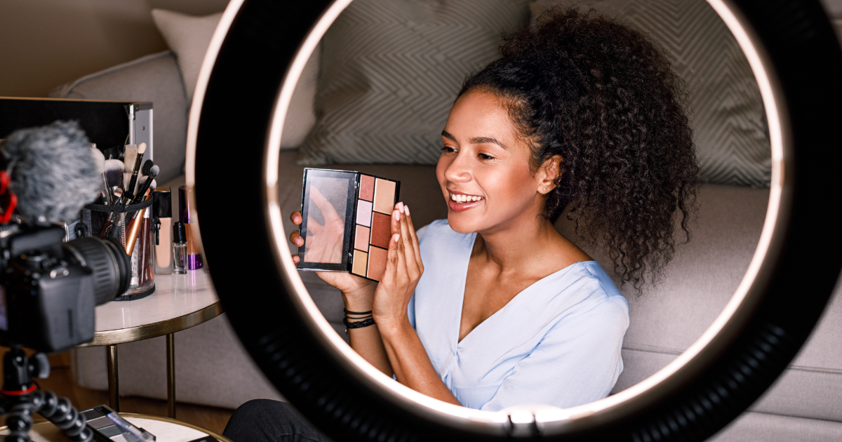 person looking into ring light holding makeup palette.