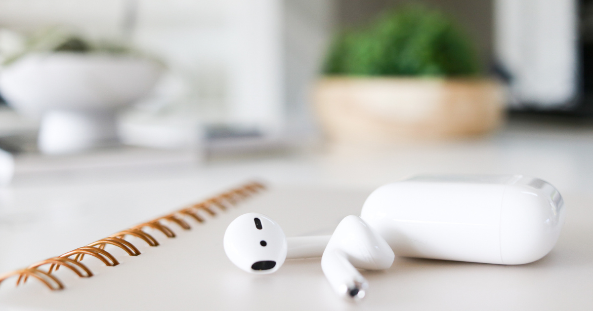 airpods and case sitting on white table.