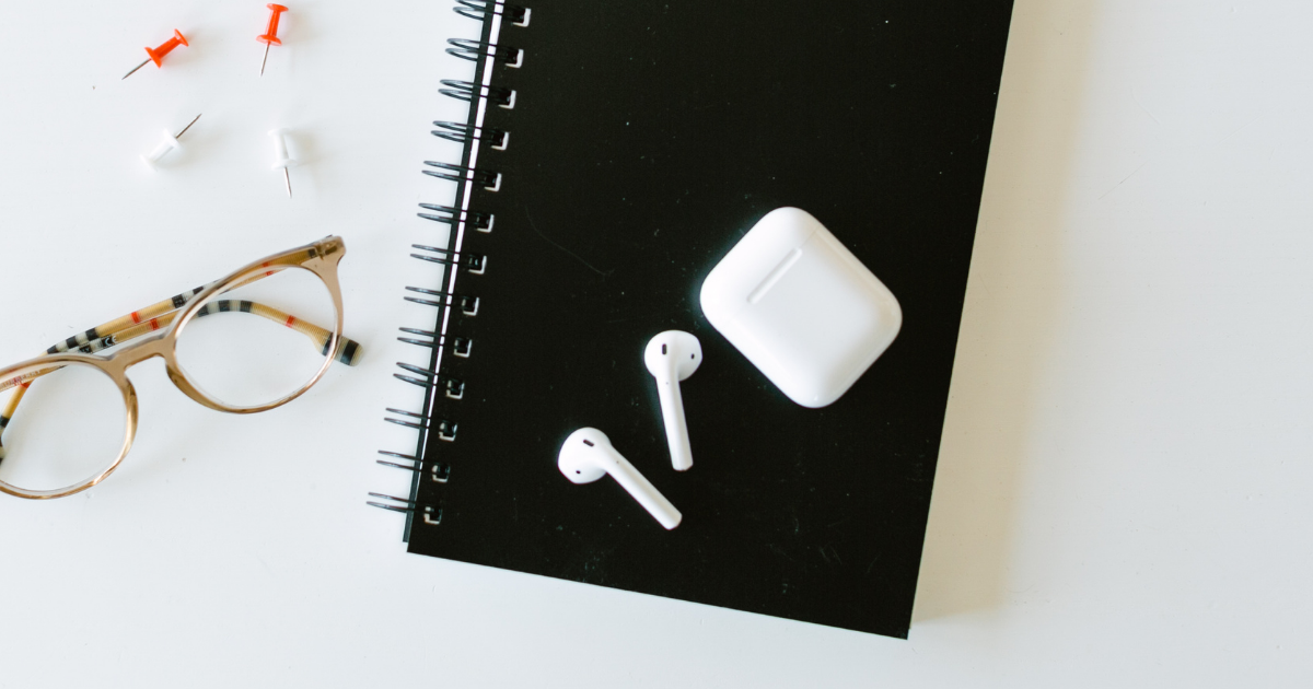 Notepad, airpods, and glasses sitting on a table.