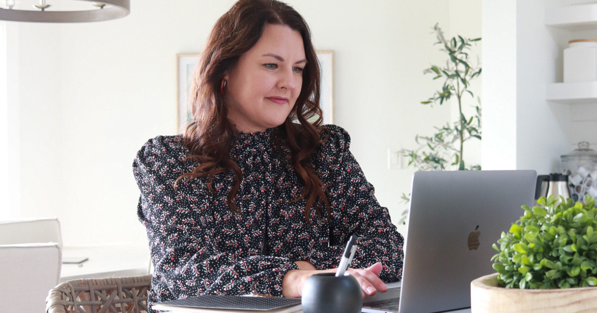 Woman using laptop at a kitchen counter.