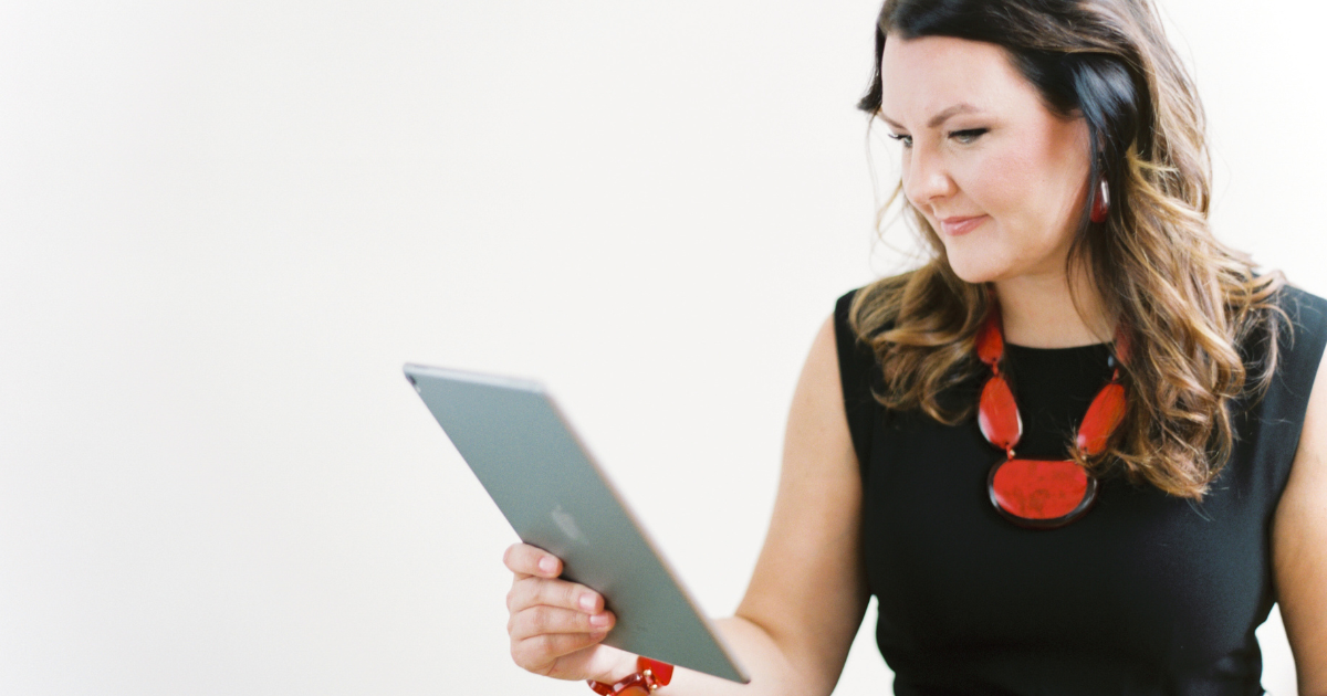 Woman holding an iPad and smiling.