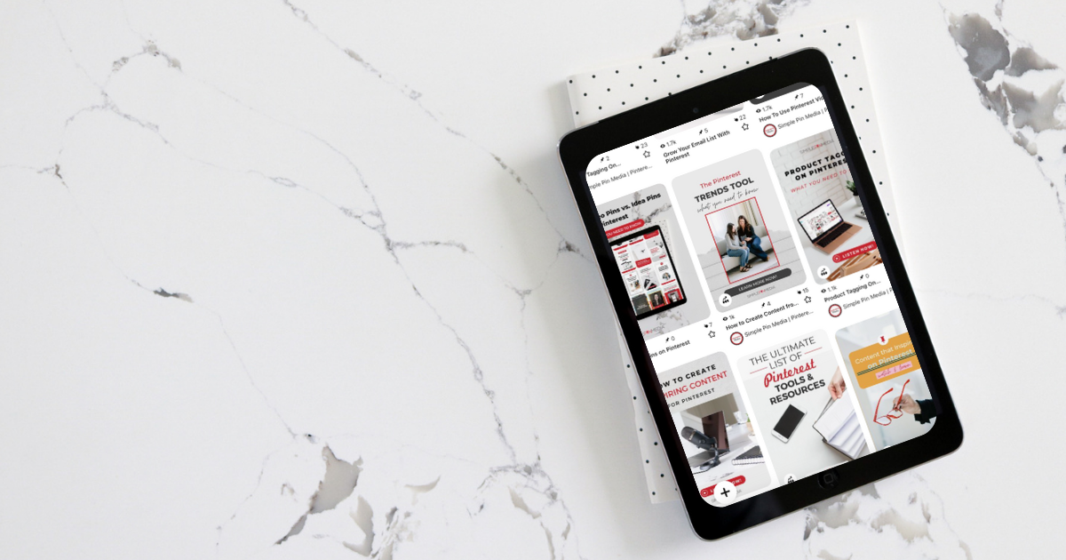 iPad lays on top of notebook. The iPad screen is open to the Pinterest feed.