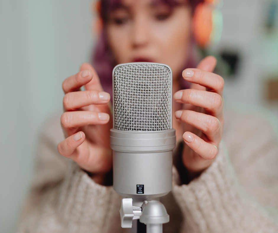 Image shows a woman tapping a microphone.